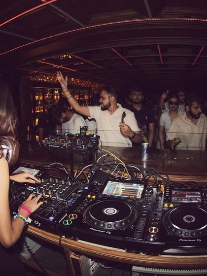 A fisheye lens captures the energy of the room, showing me at the decks and the crowd with their hands up.