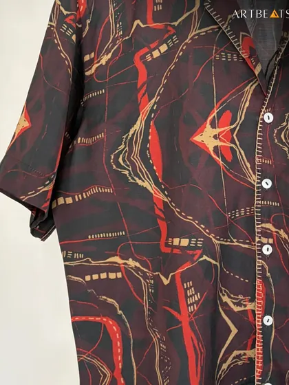 A detailed fabric shot of the Crimson Echo shirt. The deep reds and blacks are interwoven with gold and white lines, creating an echo that lingers long after the first glance.