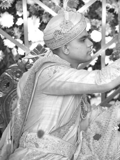 A classic black and white portrait of the groom during the wedding ceremony, his expression focused and serene.