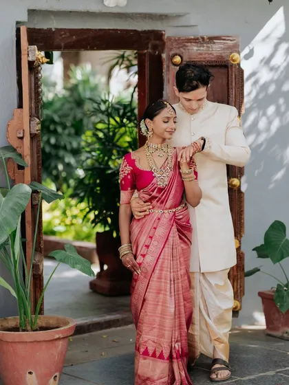 A lovely portrait of a couple framed by an antique doorway, their traditional outfits complementing the heritage feel of the space.