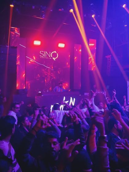 A colorful shot of the crowd at SinQ, with blue and red lights washing over them as they dance.