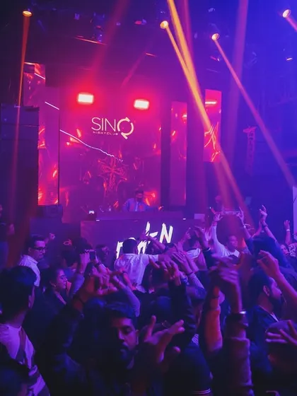 A colorful shot of the crowd at SinQ, with blue and red lights washing over them as they dance.