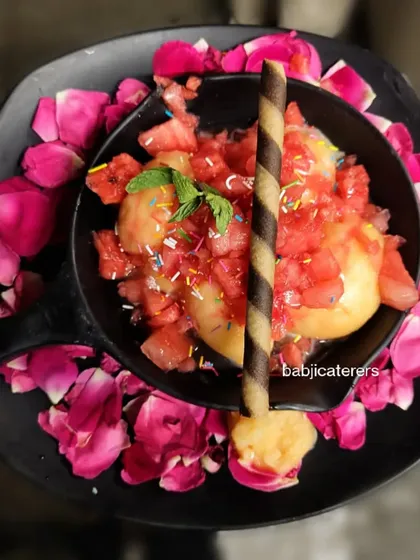 Beat the summer heat with our refreshing Watermelon Sorbet. It's beautifully presented with fresh watermelon chunks, a chocolate stick, and a sprinkle of color, served on a bed of rose petals.