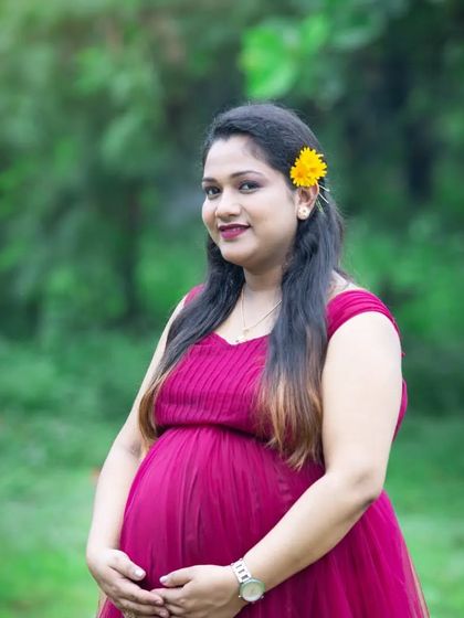 A lovely portrait with a yellow flower tucked in her hair. The rich magenta of her dress and the lush green background create a vibrant, colorful scene.