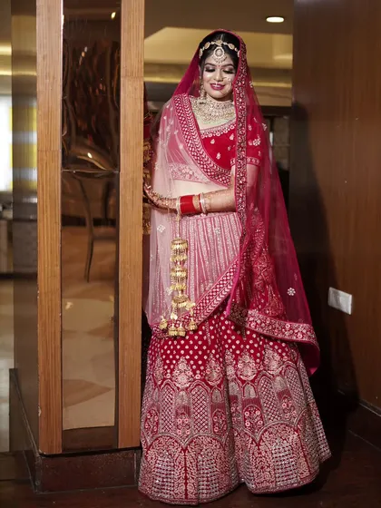 A beautiful, smiling portrait of the bride in her red lehenga, holding her kalire. This is a classic shot that every bride wants in her wedding album.
