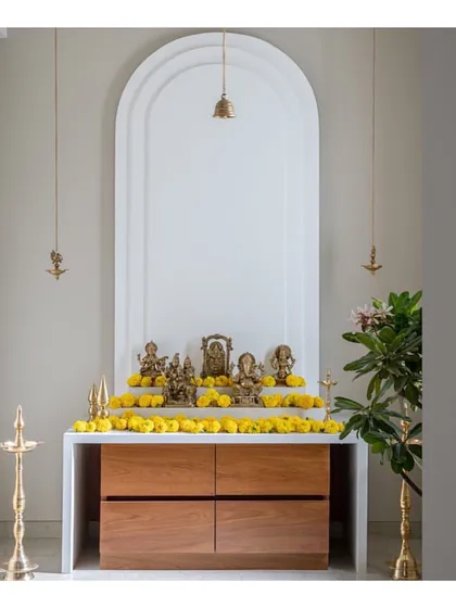 The completed mandir, adorned with fresh marigolds. The pure white arched backdrop makes the brass idols and lamps shine, creating a truly divine and peaceful space.