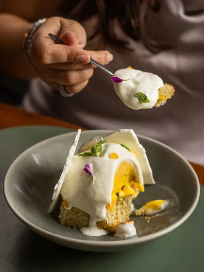 A guest enjoying a spoonful of the Tropical Pavlova, a perfect bite of cake, sorbet, and cream.