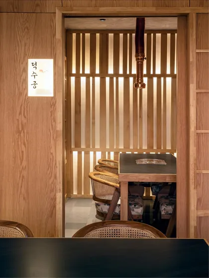 A glimpse into one of Seoul's private dining rooms. The slatted wooden screen allows light to filter through while providing privacy, creating an intimate space that feels both exclusive and connected to the restaurant's overall aesthetic.