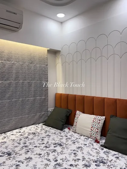 A closer look at the bedroom's feature wall with its unique scalloped molding. Paired with the vibrant orange headboard, this design element adds texture and personality to the space.