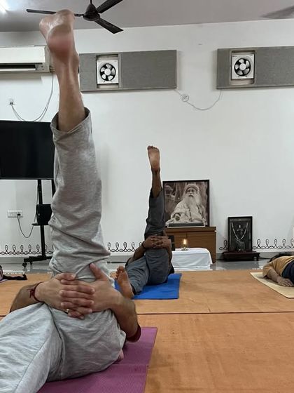 Participants practicing Sarvangasana, the shoulder stand, known as the "queen of asanas" for its many benefits.
