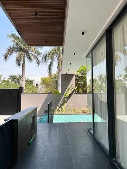 The Gulmohar Farmhouse features a poolside veranda with a wood-panelled ceiling, creating a seamless transition from the interior living space to the outdoor leisure area.