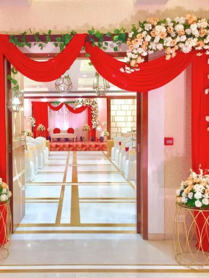 A bold and passionate entrance with rich red drapes and a floral arch of white and peach roses, creating a dramatic and romantic welcome for guests.