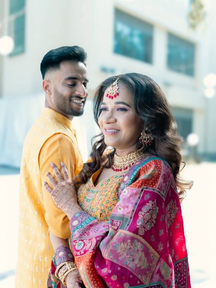 A sunlit portrait of a couple in vibrant yellow and pink outfits.