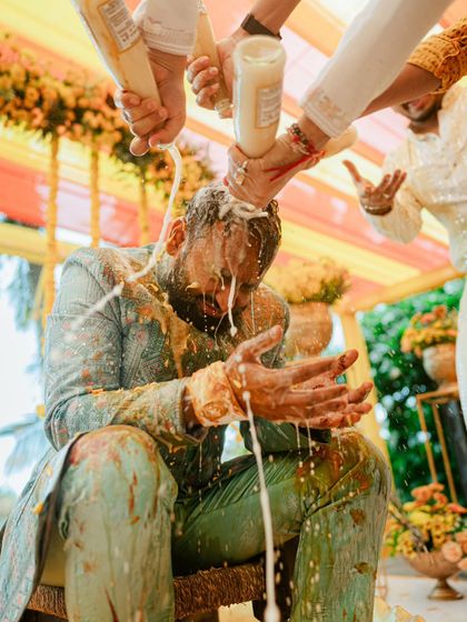 A dramatic shot of the groom being doused with buttermilk, a fun and messy tradition captured in perfect detail.