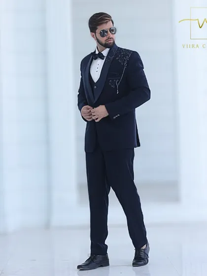The complete look of our custom navy embroidered tuxedo, styled for a formal event. The perfect fit and unique detailing make it an ideal choice for a groom's wedding reception outfit.