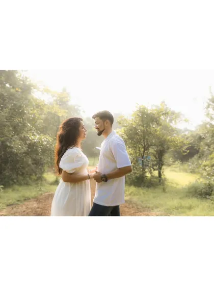 A beautiful, sun-drenched shot of the couple in a green clearing, showcasing the soft, natural light of the outdoors.