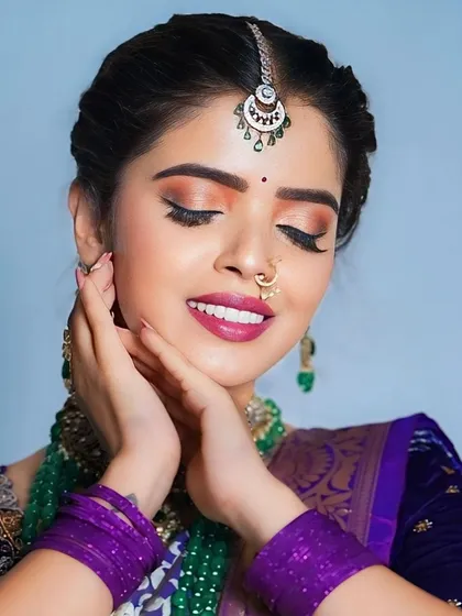 A close-up of the model's face, showing the intricate details of the maang tikka and the earrings.