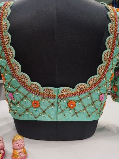 A beautiful pastel green blouse with a scalloped neckline. The design features a lattice pattern with floral motifs in orange and pink, perfect for a spring wedding.