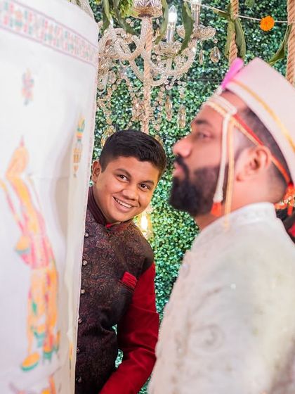 The 'Antarpat' moment in a Marathi wedding, where the groom waits eagerly to see his bride. The peek from the side adds a touch of fun to this traditional moment.