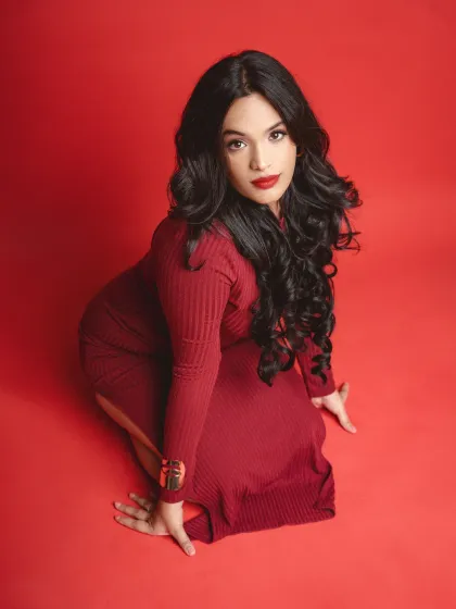 A high-angle shot from the red background series. This perspective creates a unique composition, emphasizing the model's pose and the flow of her dress.