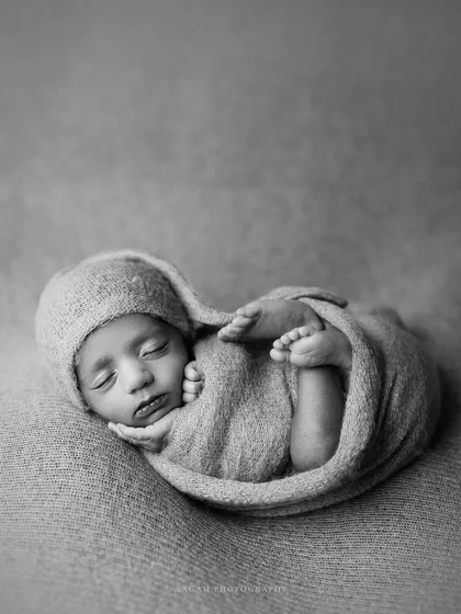 Another "lil peanut" pose, this time showing the baby curled up snugly. The black and white treatment gives it a timeless, artistic feel.