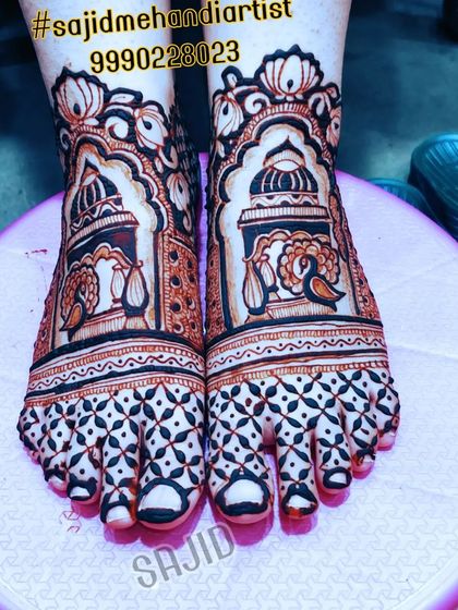 This bold feet design features architectural domes and peacock motifs. The toes are covered with a dense, dark geometric pattern, creating a striking contrast that is popular in bridal mehandi.
