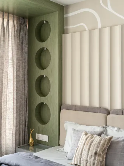 This kids' bedroom seamlessly blends functionality with a sage green alcove featuring circular recesses, offering a visually engaging yet functional display area for décor or toys. A harmonious play of textures and tones makes this a serene yet stylish retreat.