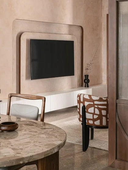 The view from the dining area into the living space, framed by a custom wooden partition with fluted glass. The rust tones and patterns flow from one room to the next, creating a cohesive yet distinct feel for each area.