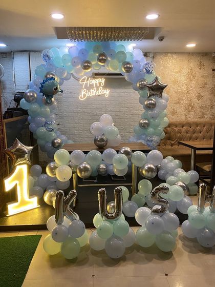 A full view of the dinosaur-themed first birthday setup, including letter balloons spelling out the name 'KUSH'.