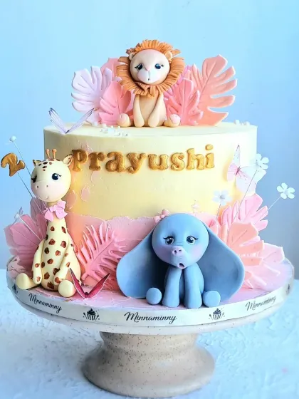 A full view of the two-tier safari cake, showcasing the balanced arrangement of the fondant animals and decorative elements.