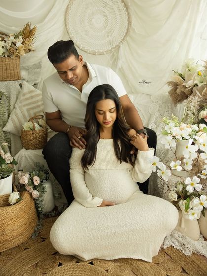 A relaxed and loving moment between a couple during their family maternity shoot. The soft, neutral tones of the setup create a warm and inviting atmosphere.