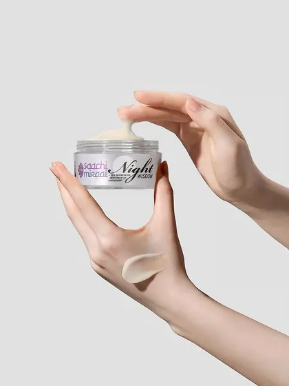 A close-up of Saachi Mirai's Night Wisdom cream, showing its rich texture being scooped from the jar. Hand-interaction shots like this make the product feel more tangible and relatable.