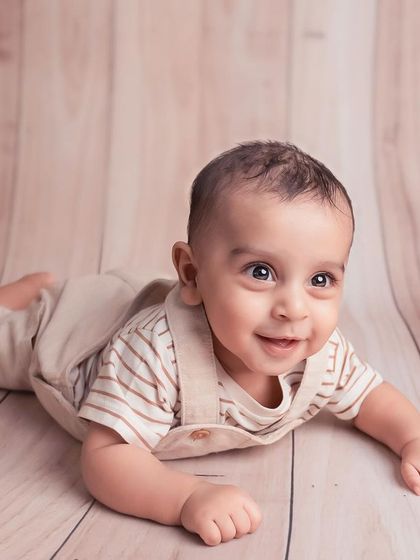 That smile is everything! A simple portrait on a wooden background allows this baby's happy expression and bright eyes to be the complete focus.