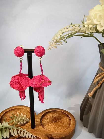 A product shot of the hot pink drop earrings, highlighting their intricate beaded design.