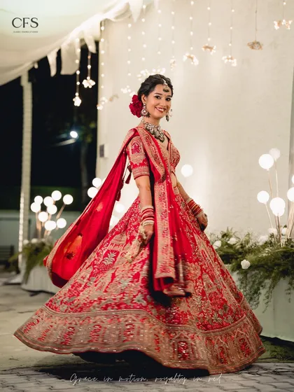 A radiant bride twirling in her red lehenga. This shot captures the joy and movement of the celebration, with beautiful bokeh lights in the background.