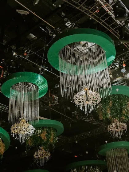 An upward shot focusing on the custom ceiling structures, showing how the crystal tassels and chandeliers are integrated with hanging floral arrangements for a lush, garden-like feel.