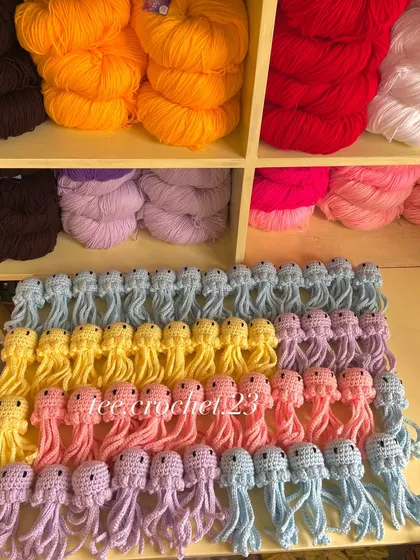 Rows of my pastel amigurumi jellyfish, available in lilac, blue, yellow, and pink for bulk orders.