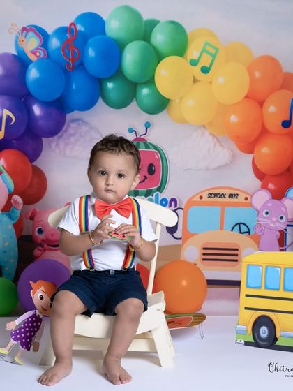 A full view of our vibrant Cocomelon themed setup for a first birthday, with the baby boy sitting proudly amidst all his favorite characters.