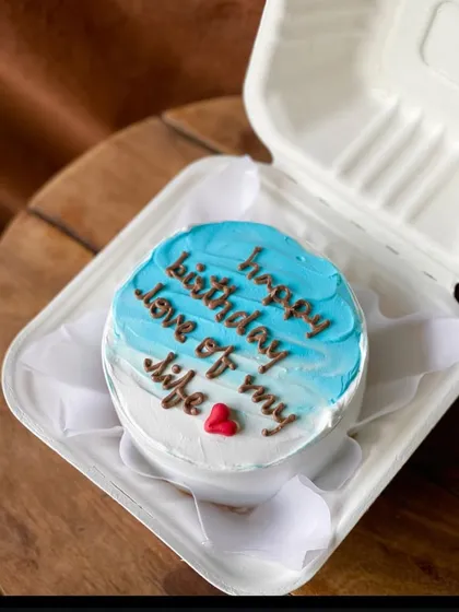 A beautiful ombre bento cake with blue and white frosting, carrying the heartfelt message "happy birthday love of my life." A single red heart completes this romantic gesture.