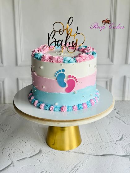 Oh Baby. A simple and sweet gender reveal cake with pink and blue stripes and tiny footprints, topped with a golden "Oh Baby" sign.