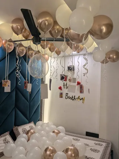 A close-up of the hanging photos and balloons over the bed, showing the detail of the personalized birthday decorations.