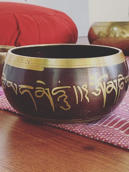 A close-up of a Tibetan singing bowl, etched with the sacred mantra 'Om Mani Padme Hum'. These instruments are not just beautiful objects but are tools for Nada Yoga, the yoga of sound, used for centuries to promote healing.