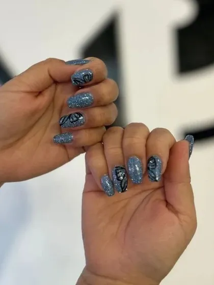 A fun pose showing off the blue glitter and butterfly wing nail art. This set is whimsical and eye-catching.