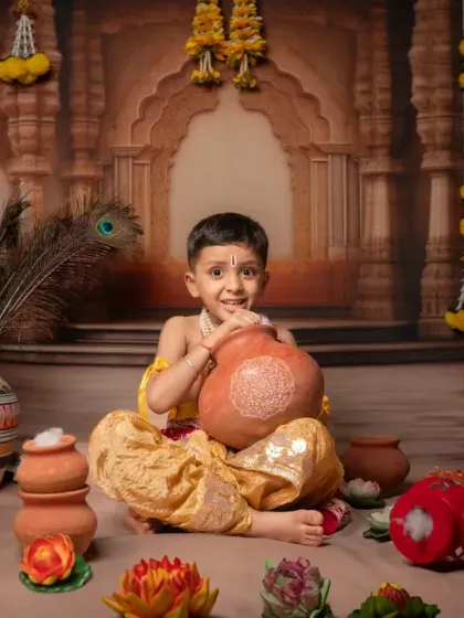 Capturing the innocent and mischievous spirit of 'Natkhat Nandlal'. This little boy, dressed as Krishna, has a playful moment with a pot of butter during his themed studio session.