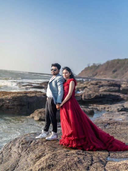 A romantic pose by the sea. This couple's pre-wedding shoot captures a quiet moment, with the bride in a beautiful ruffled red gown.