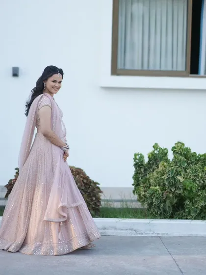 A full-length shot of Dr. Krishnaveni in her elegant reception lehenga. She looks graceful and beautiful.