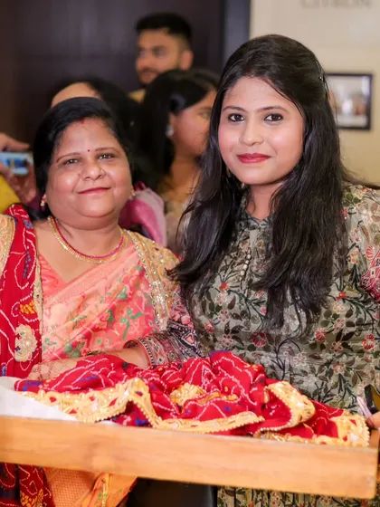 Two women carrying a tray with traditional offerings during a wedding ritual, their expressions showing their important role in the ceremony.