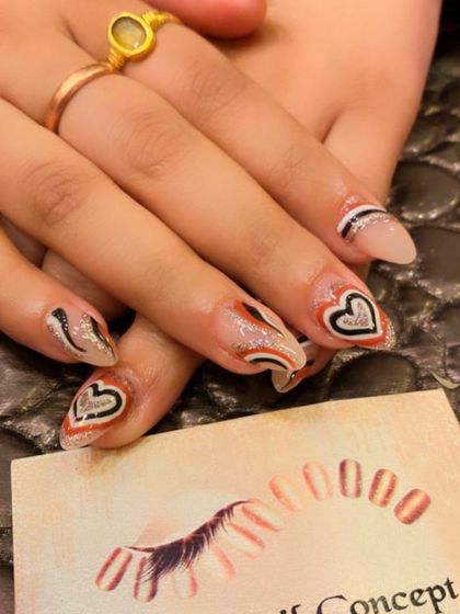 A unique and artistic design on clear almond nails. The nails are decorated with hand-painted heart outlines and abstract swirls in black, white, and red glitter.