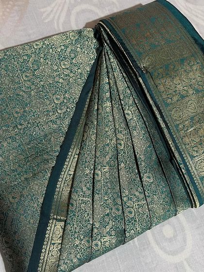 This deep teal brocade saree is heavy, but with pre-pleating, it becomes much easier to manage and drape elegantly.