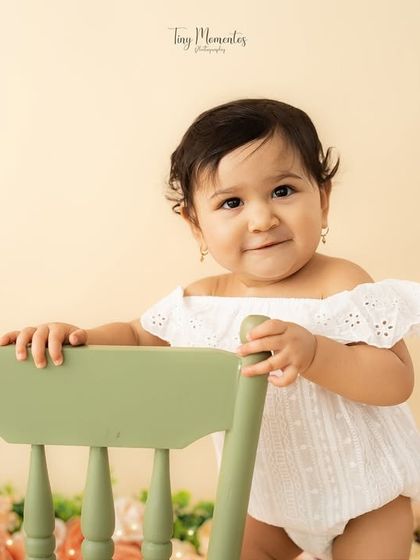 A sweet and steady pose. This portrait captures her calm and curious nature amidst a soft, floral setting.